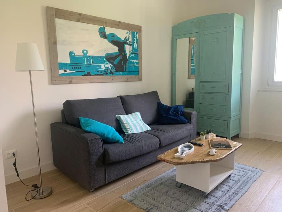 Soggiorno con divano grigio, armadio turchese e quadro decorativo