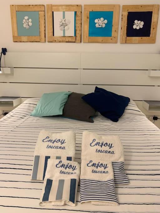 Letto matrimoniale con asciugamani Enjoy Toscana e quadri sopra