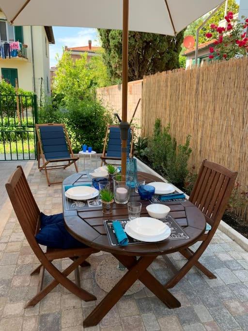 Tavolo apparecchiato in giardino con ombrellone e sdraio blu